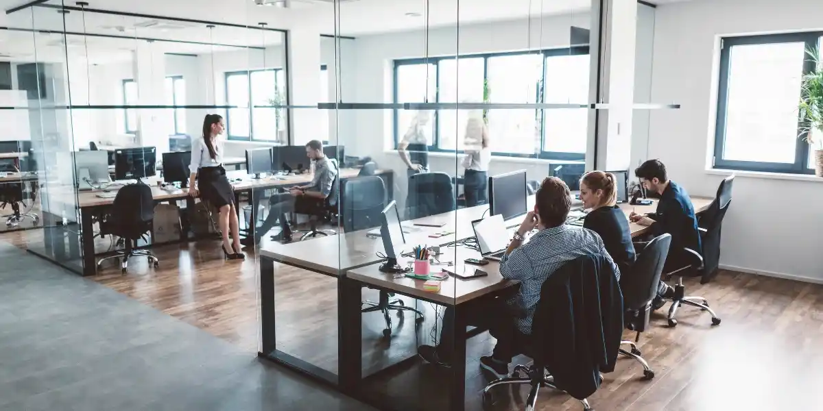 Oficina corporativa moderna con equipos de trabajo colaborando, representando el avance y protección de tu empresa